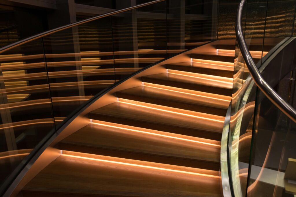 Curved staircase with glass and LED lighting creating luxury ambiance.